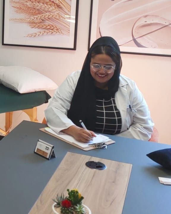 Dr Patel writing notes at her consultation desk in a sunlit treatment room